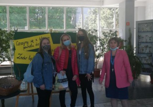 Pani dyrektor i trzy uczennice stoją przy koszu z cukierkami przy wejściu