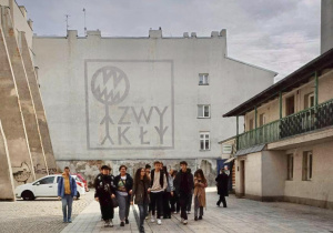 Uczniowie spacerujący w tle mural grupy tworzywo w bramie przy Piotrkowskiej 26