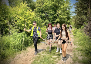 Grupa uczniów idzie drogą przez las