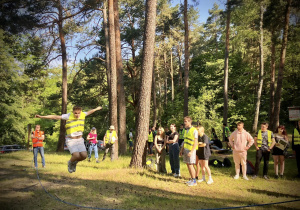 Uczniowie skaczą przez linę wykonując zadanie sportowe na trasie rajdu
