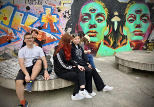 Uczniowie siedzą na ławce pod muralem na Off Piotrkowska