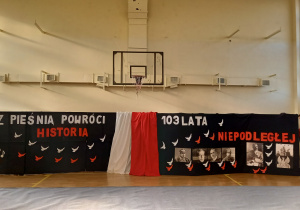 Dekoracja szkolnego apelu z napisami z pieśnią powróci historia, 103 lata niepodległej wraz ze zdjęciami