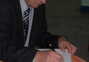 Kazimierz Tischner wpisuje się do księgi pamiątkowej
